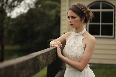 Keywords: bride,lady,girl,standing,railing,bare arms,white dress,headband,brown hair,house in background,greenery