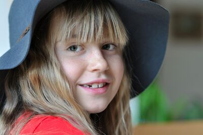 Keywords: girl,child,blue floppy hat,red shirt,blonde hair,looking over her shoulder