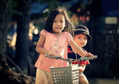 Keywords: portrait,child,kid,children,girl and boy,bicycle,peach top,hat,necklace,flowers,shirt,red,blue,stripes,basket