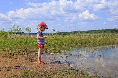 Keywords: girl,girl standing,lake,grass,stick,water,cap,pink,shorts,cloudy sky