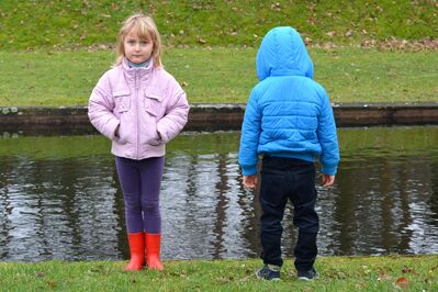 Keywords: portrait,kids,children,two,red boots,purple leggings,pink jacket,jeans,blue hooded,facing front,back,stream,river,grass,green,cold