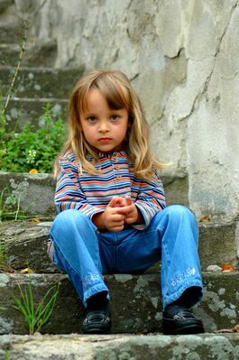 Keywords: portrait,girl,sitting,stone steps,hands,blonde,young,striped shirt,blue,orange