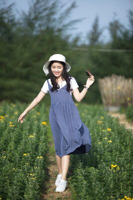 Keywords: girl,walking in a garden,white hat,shirt,tennis,blue jumper,rows of flowers,green trees