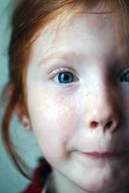 Keywords: portrait,girl,red hair,facial expression,blue earring,freckles,red top