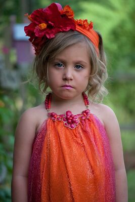 Keywords: girl,kid,child,orange and red dress,red flower in hair,hairband,frown,blande,green background