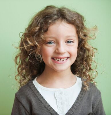 Keywords: girl,portrait,curly blonde hair,gap,teeth,white shirt,grey sweater