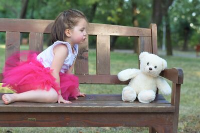 Keywords: girl,barefoot,pink tutu,young,teddy bear,bench,outdoors