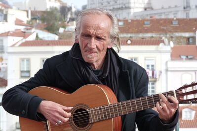 Keywords: musician,guiter,old man,goatee,dark jacket,buildings,outdoors,playing