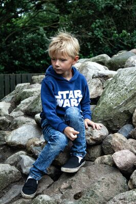 Keywords: boy,sitting on rocks,jeaans,blue and white pullover,blonce hair