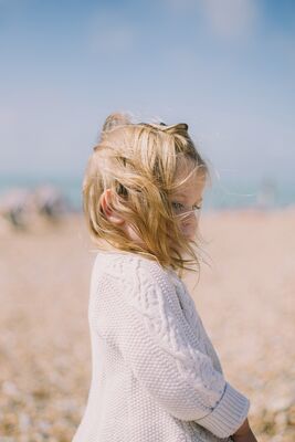 Keywords: girl,white top,youth,young,hair,kid,sand,outdoors,wind