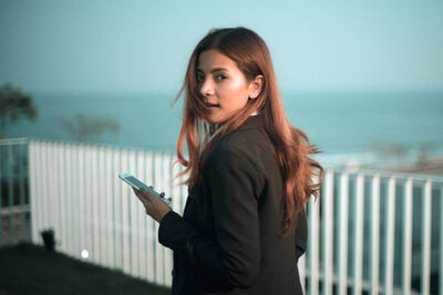 Keywords: profile of a girl with red hair blowing in the wind,beach,fense,wind,girl,red hair