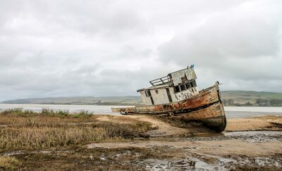 Keywords: beach,sky,grey sky,sea,seashore,bay,old boat,clouds,broken boat,fishing