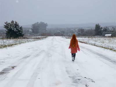 girl-walking-on-snowy-country-road
