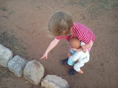 Keywords: child,doll,lizard,discovery,rocks,pointing,girl