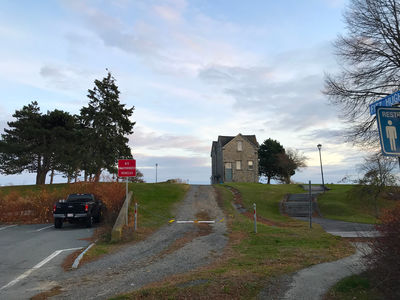 Keywords: house,road,solitary house,leaning trees,trees,blue sky,auto,automobile,truck,treet sighs,street sign,painting a house with tilted trees across the road